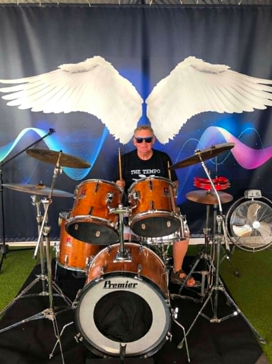 Frank at the drums with angel wings backdrop